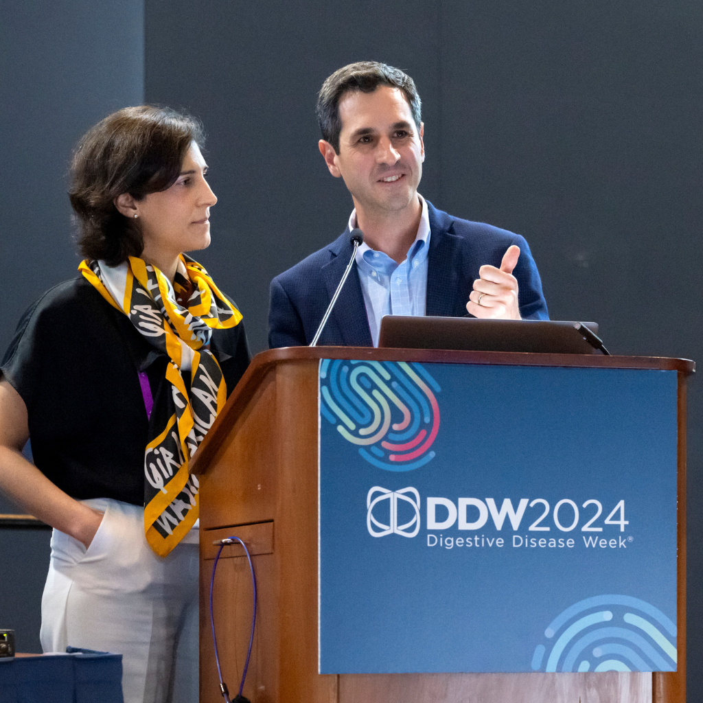 Image of two people speaking in front of a podium.